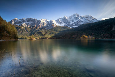 Scenic view of lake by snowcapped mountains against sky