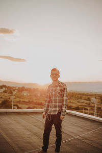 Man standing on terrace against sky during sunset