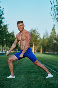 Portrait of shirtless man exercising on field