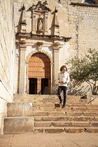 Full length of woman leaning on staircase of building