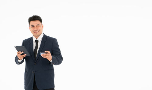 Man holding camera while standing against white background