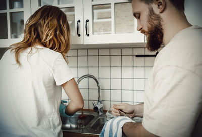 Couple cleaning utensils at sink