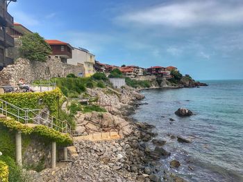 Scenic view of sea by buildings against sky