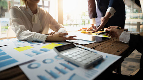 Midsection of business colleagues working on table