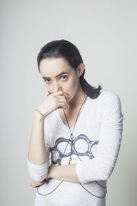 Portrait of young woman standing against white background