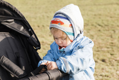 Cute girl playing with baby stroller on field