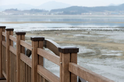 Wooden railing by sea against mountains