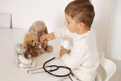 Cute little boy playing doctor at home and curing plush toy. sweet toddler child plays indoor.