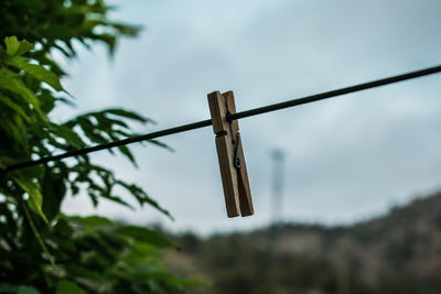 Low angle view of clothespins on rope against sky