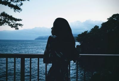 Woman standing by railing against sky