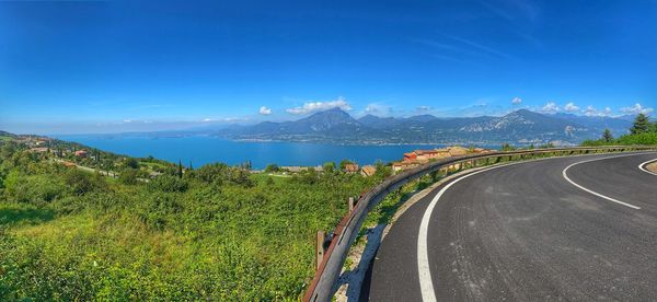Panoramic shot of road by mountains against blue sky
