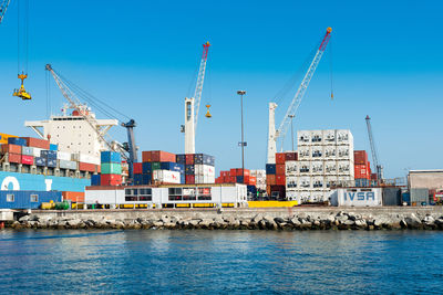 Cranes at harbor against blue sky