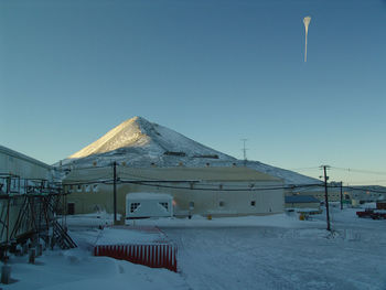 Built structures on snow covered mountain against clear blue sky