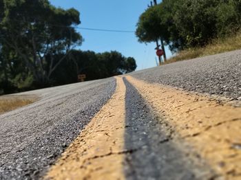 Surface level of road by trees against sky