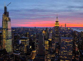 Illuminated buildings in city against sky during sunset