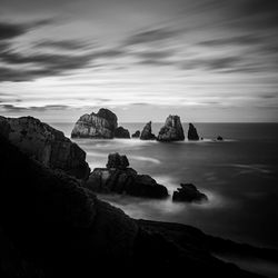 Rocks on sea shore against sky
