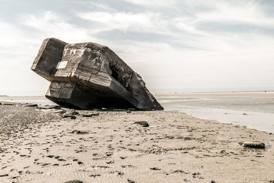 Abandoned boat on beach against sky