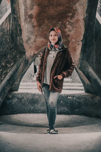 Full length portrait of woman standing against wall during winter