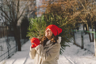 Portrait of smiling young woman standing against trees