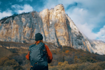 Rear view of man standing on rock against sky