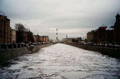 Surface level of canal amidst buildings against sky