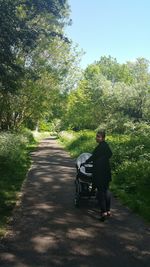 Man walking on road amidst trees against sky