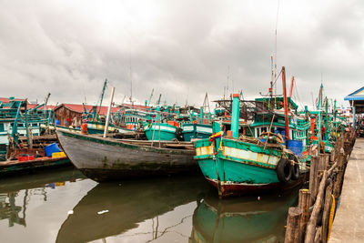 Boats moored at harbor against sky