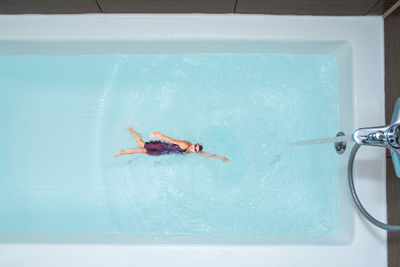 Digital composite image of woman swimming in bathtub