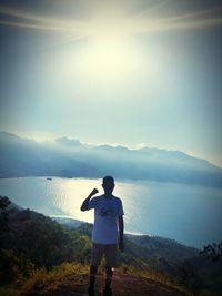 Rear view of man standing on mountain against sky