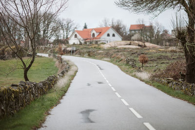 Empty road amidst houses and trees in city