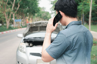 Man photographing with mobile phone in car