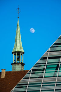 Historic tower next to the modem library in ulm with the moon