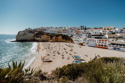 Scenic view of beach by buildings against clear blue sky