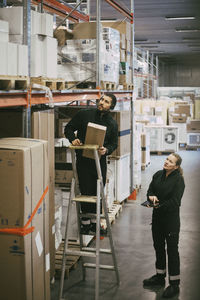 Male entrepreneur analyzing packages with female colleague in warehouse