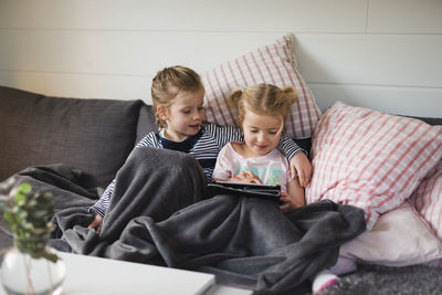 Sisters using digital tablet on sofa