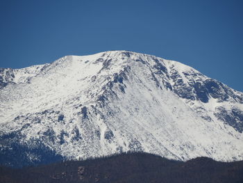 Low angle view of snowcapped mountains against clear blue sky