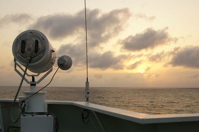 Lighting equipment on boat in sea against sky during sunset