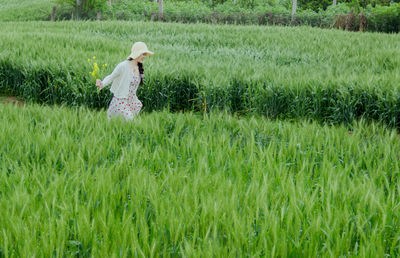 Rear view of woman with arms outstretched on grassy field