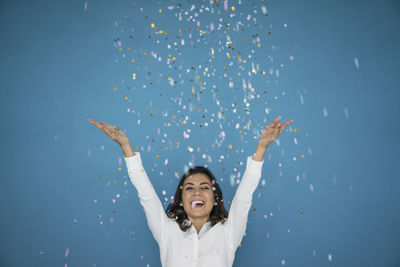 Portrait of laughing woman throwing confetti in the air