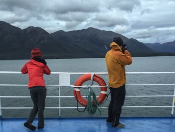 Rear view of man and woman on boat deck in sea