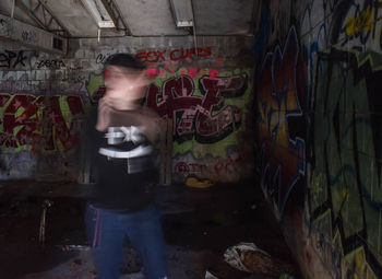 Man standing by graffiti on wall