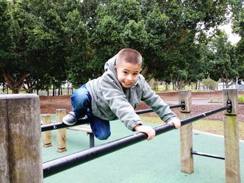 Portrait of boy playing with railing at park