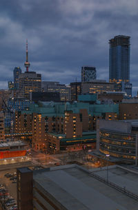 Modern buildings against cloudy sky in city at dusk