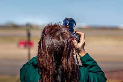 Rear view of woman photographing against sky