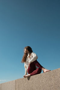 Low angle view of woman against clear blue sky