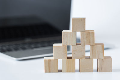 Close-up of stacked wooden toy blocks by laptop on table