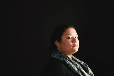 Portrait of beautiful young woman over black background