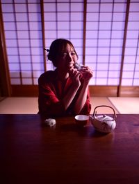 Young woman drinking drink sitting on table