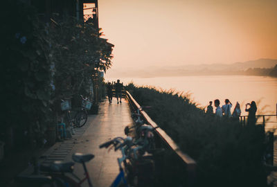 People at riverbank against clear sky