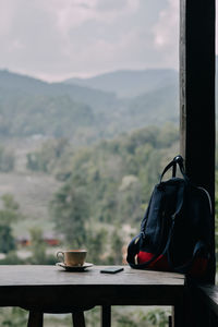 Coffee cup on table against mountains